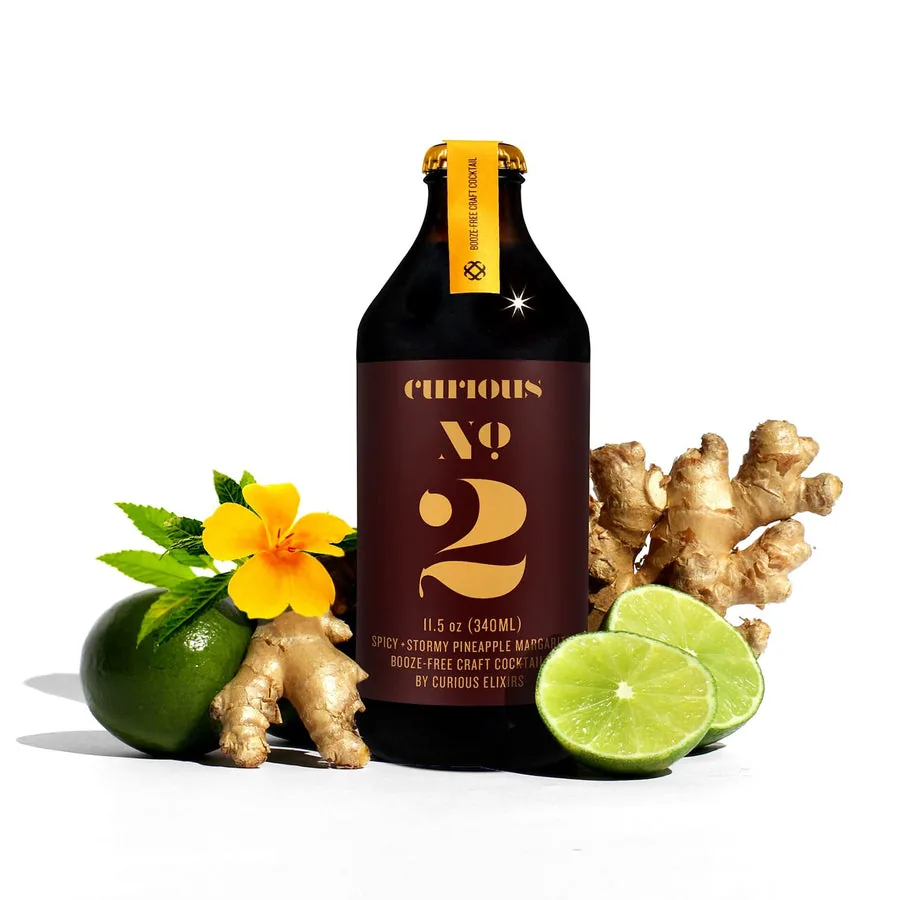 Curious No. 2, a non-alcoholic Spicy Pineapple Ginger Margarita, beside fresh ginger and lime.