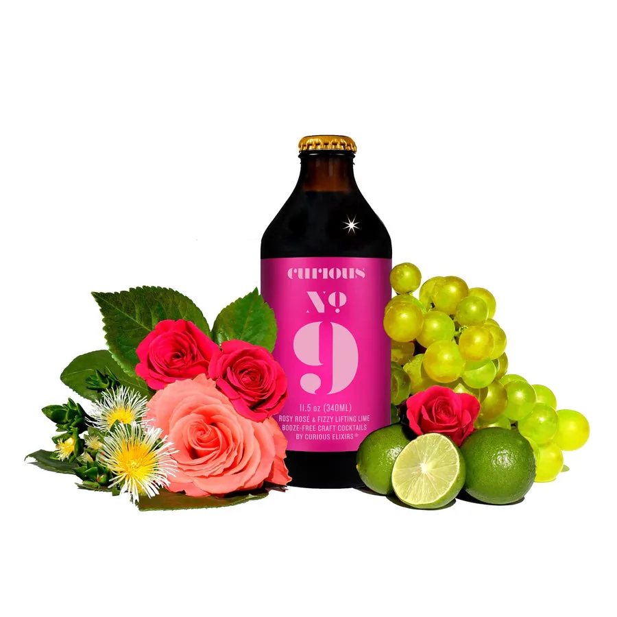 Curious No. 9, a non-alcoholic Sparkling Rosé Cocktail, beside roses, grapes, and lime.