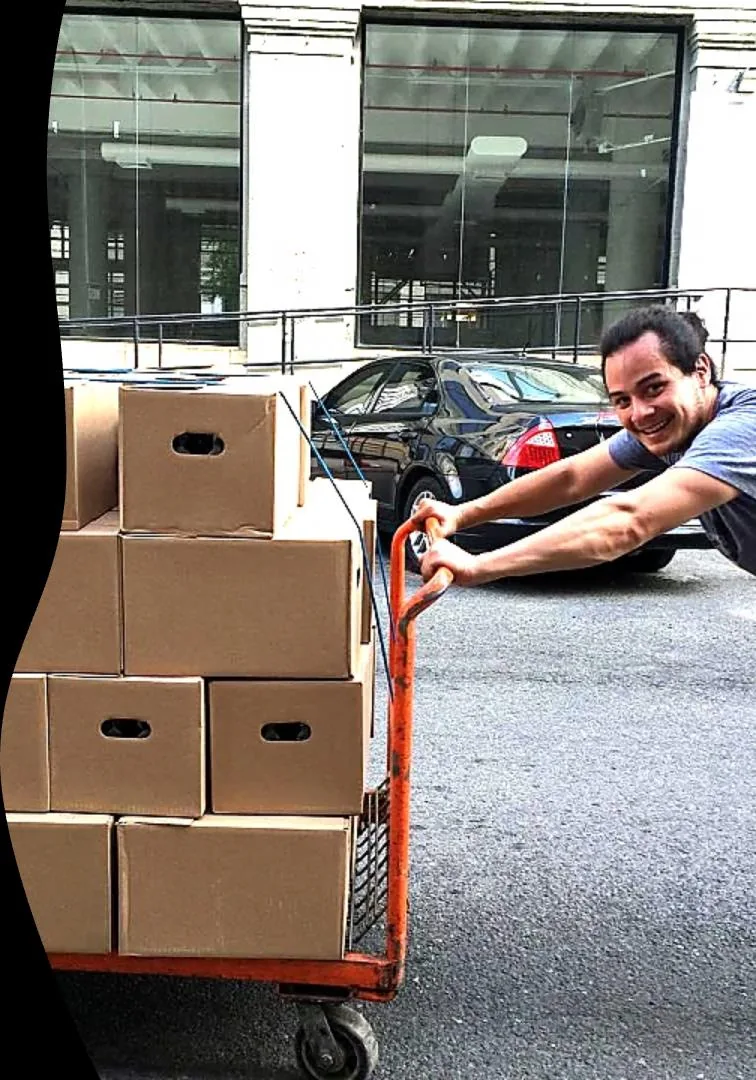Matt Wallace, Founder and CEO of JAI Development, hauling a cart of CPG product cases out of a Brooklyn warehouse loading dock